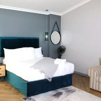 Teal upholstered double bed with soft grey throw