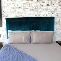 Teal velvet headboard against exposed white brick wall