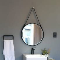 Round black-framed mirror above a vessel basin